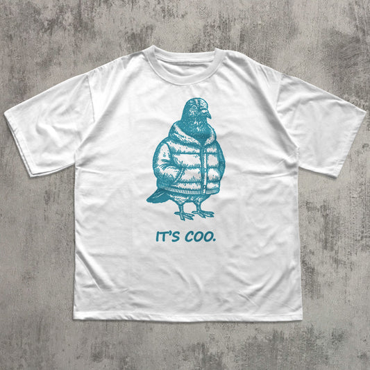 White graphic t-shirt featuring a funny illustrated pigeon wearing a puffer jacket with the slogan “It’s Coo,” a minimalist unisex casual tee with a quirky bird design for everyday wear