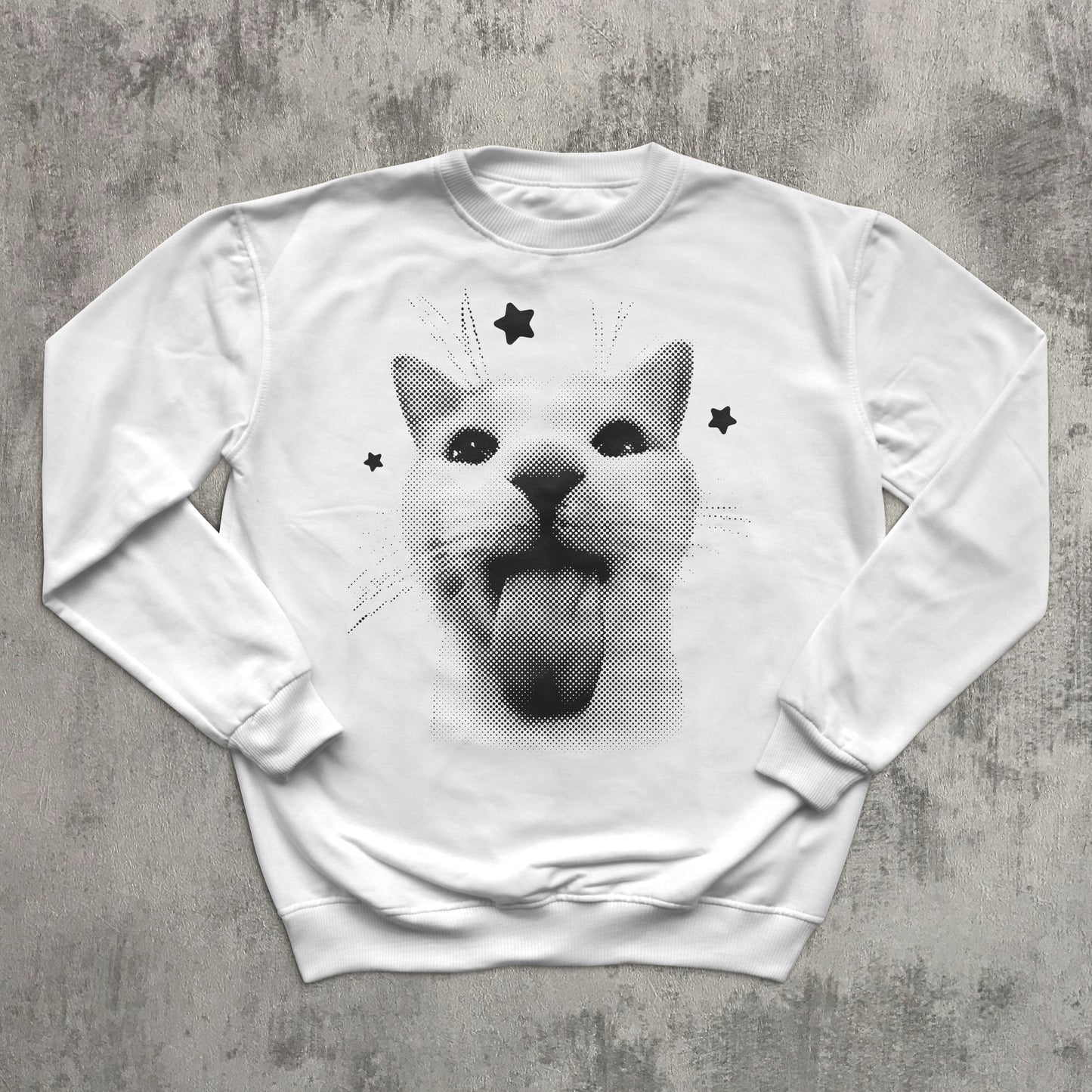 White sweatshirt with a graphic of a cat with stars on a gray surface