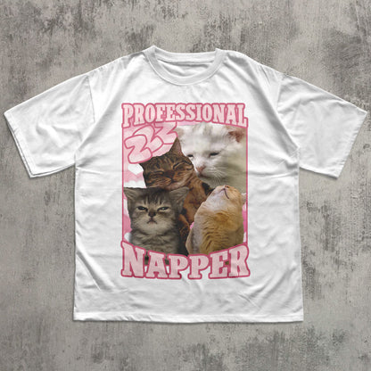 Funny White t-shirt with a graphic of cats and the text 'Professional Napper' on a concrete surface.