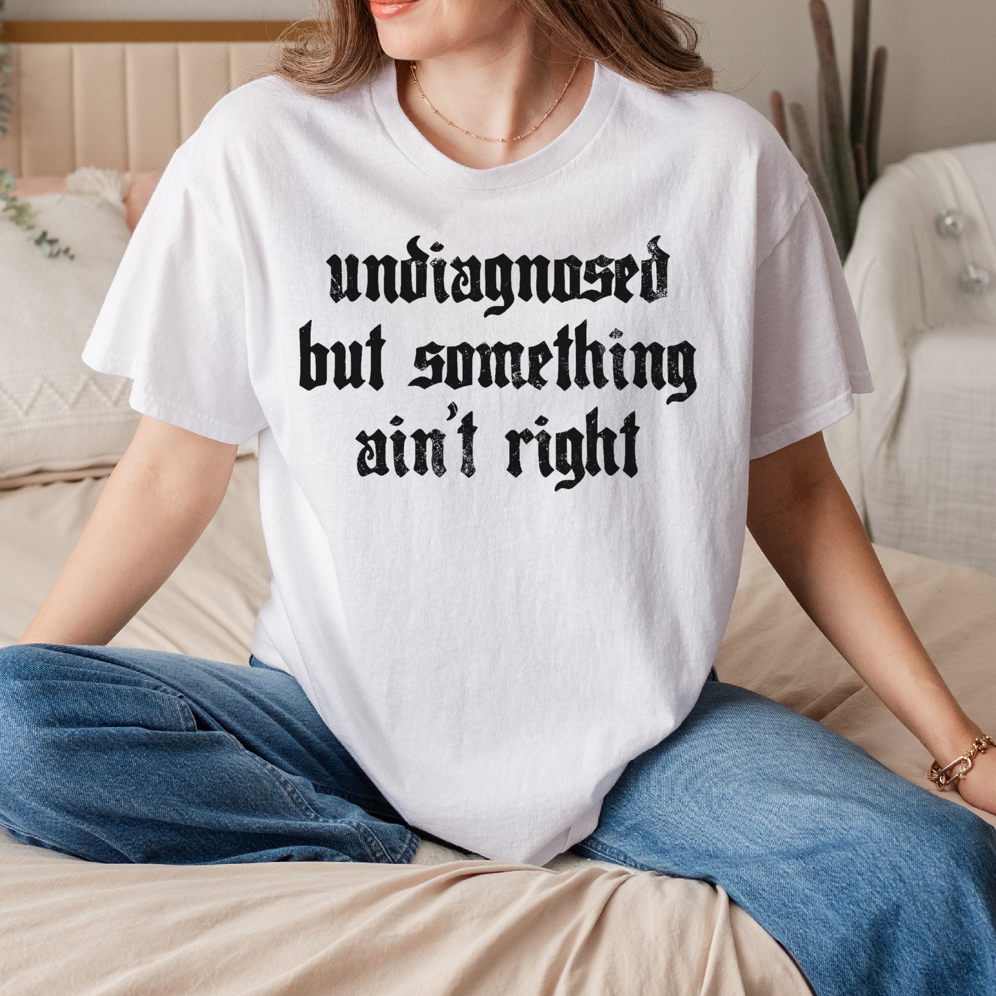 Person wearing a white t-shirt with text sitting on a couch.
